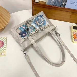 Detailansicht der grauen ITA-Tasche mit transparentem Fenster und Anime-Anstecknadeln