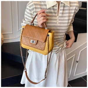 Detail of a brown and yellow quilted crossbody bag featuring a metal turn-lock and chain strap