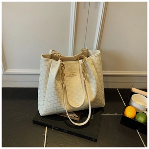Détail du cabas imprimé monogramme avec chaîne en métal et bandoulière en cuir réglable