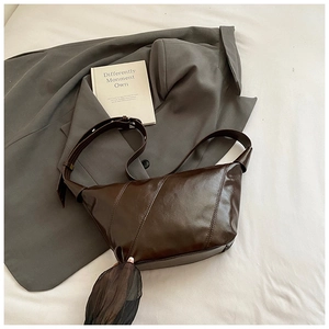 Détail d'un sac hobo en cuir marron foncé avec coutures diagonales et bandoulière réglable
