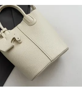 Close-up of cream leather bucket bag showing soft lychee texture and elephant charm