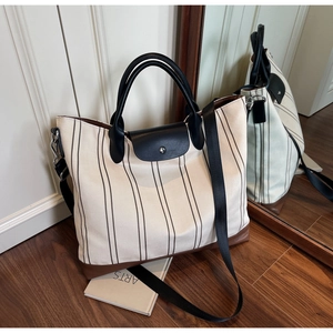 Detailed view of striped canvas tote with black leather trim and adjustable strap