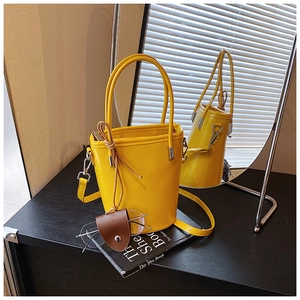 Detailed shot of a bright yellow leather bucket bag with top handles and silver hardware