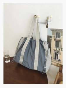 Detail of blue and beige large canvas tote bag with drawstring closure in a lifestyle setting