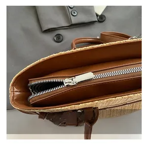 Detail view of the silver metal zipper and striped lining on woven straw tote bag