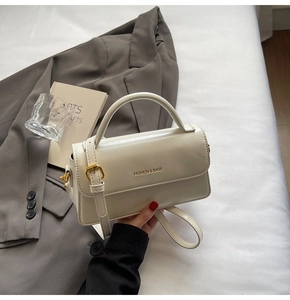 Detail of elegant cream leather handbag with gold hardware and embossed fashion logo