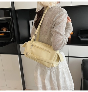 Detail of a creamy yellow PU leather pillow bag with stylish buckles and smooth finish