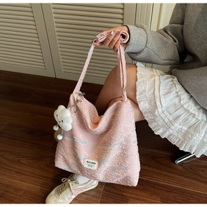 Detail of pink quilted tote bag with colorful embroidery and white plush cloud charm