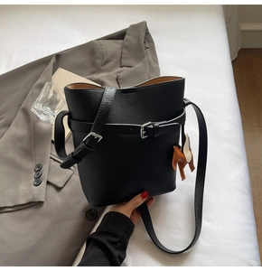 Detail of black lychee grain leather bucket bag with decorative buckle and horse charm