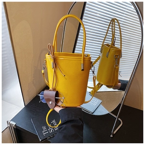 Detail of yellow PU leather bucket bag with top handles and a glasses case accessory