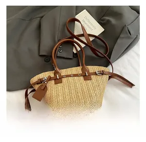 Detail of woven straw tote bag with brown leather handles and decorative metal buckle
