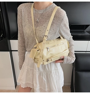 Close-up of yellow leather boston bag with metallic eyelets worn as an underarm shoulder bag