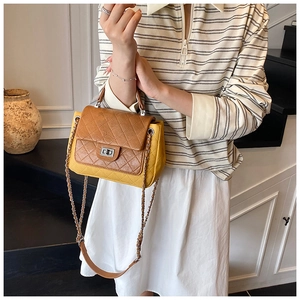 Close-up of quilted yellow and brown crossbody bag with silver twist lock and chain strap