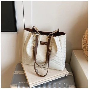 Détail d'un sac cabas crème avec motifs en relief et bandoulière en cuir marron