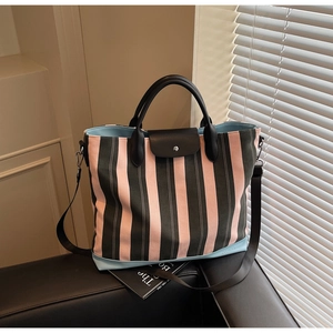 Macro detail of stripe canvas tote featuring premium black leather handle and NOCO logo
