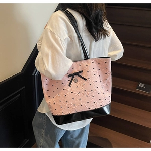 Borsa tote rosa con fiocchi neri e ciondolo a cuore su una scala in legno