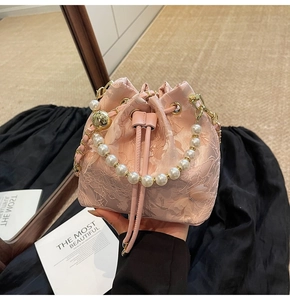 Detailed shot of pink lace bucket bag featuring pearl handle and 3D floral embroidery