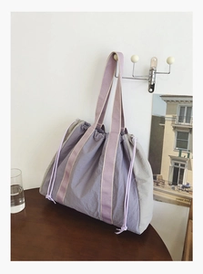 Detail of purple and grey nylon tote bag with drawstring feature on a wall hook