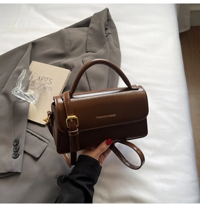 Detailed view of deep brown vintage crossbody bag with gold buckle and top handle