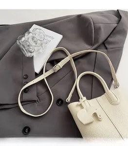 Detail of cream lychee leather mini tote bag with adjustable strap and elephant charm