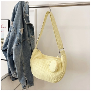 Detail of light yellow pleated crescent bag with adjustable strap and mini round pouch