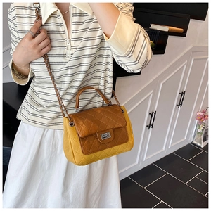 Close-up of quilted color-block crossbody bag with metal twist lock on model in soft light
