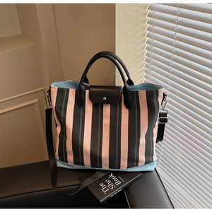 Close-up of pink striped tote bag showing leather flap and metal snap button closure
