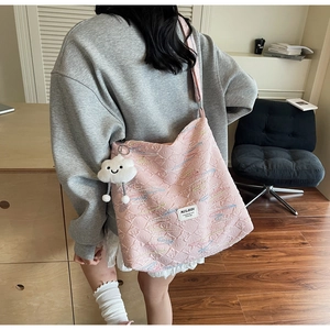 Detailed shot of pink quilted tote bag with colorful embroidery and white cloud pendant
