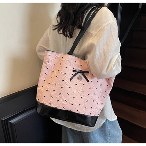 Dettaglio della borsa tote rosa con ricamo a fiocco nero e ciondolo a cuore in metallo