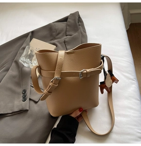 Close-up of khaki lychee texture bucket bag with decorative silver buckle and horse charm
