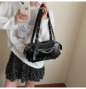 Detail of black glossy patent leather Boston bag featuring silver eyelets and multi-zippers