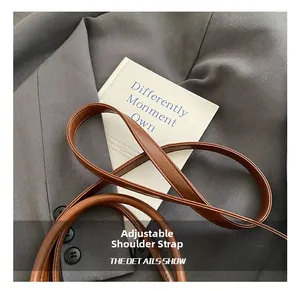 Detailed view of the adjustable brown leather shoulder strap with premium stitching