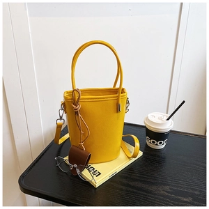 Close-up of bright yellow bucket bag with lychee texture and silver hardware