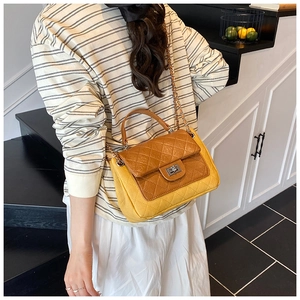 Detail of yellow and brown quilted crossbody bag with chain strap and silver twist lock