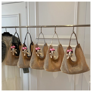 Detail of woven straw hobo bags in five colors with cute dog charms on a white wall