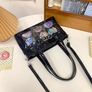 Detail einer schwarzen Lackleder Ita-Bag mit Sichtfenster und Herz-Ketten-Accessoires
