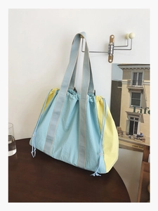 Detail of blue and yellow contrast tote bag with drawstring closure on a metal hook