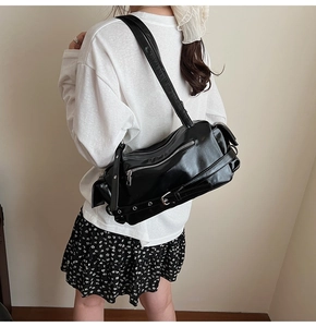 Detail of black faux leather shoulder bag with silver zippers and buckle straps