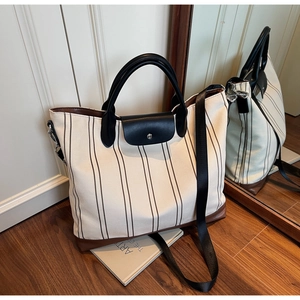 Close-up of striped canvas tote bag with leather contrast and crossbody strap