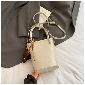 Detail of cream bucket bag with lychee texture faux leather and decorative side straps