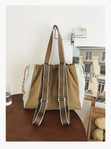 Detail of canvas tote bag featuring khaki and light blue color block and drawstring closure