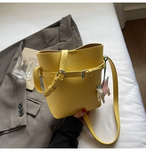 Detail of yellow bucket bag with lychee texture and cute elephant charm on fabric
