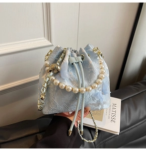 Detail of light blue embroidered bucket bag with pearl handle and lace butterfly texture