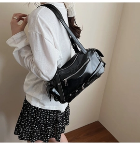 Detail of black faux leather shoulder bag with silver zippers and metal eyelet straps
