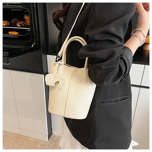 Detail of off-white leather bucket bag with cute elephant charm and crossbody strap