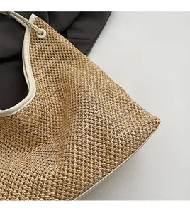 Close-up of woven straw tote bag featuring white leather piping and soft natural texture