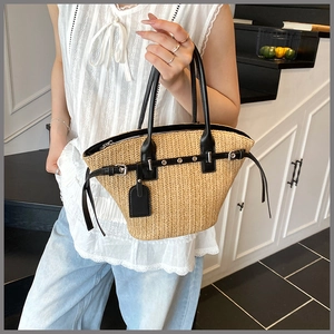Detail of woven straw tote bag with black leather handles and secure metal zipper