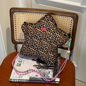 Detail of star-shaped leopard print bag with colorful woven strap on a vintage chair