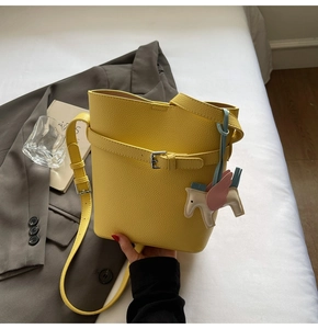 Detail of yellow lychee texture bucket bag with decorative strap and pegasus charm
