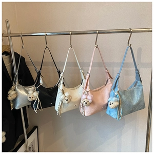 Détail de sacs hobo en argent, noir, blanc, rose et bleu avec charms ours peluche